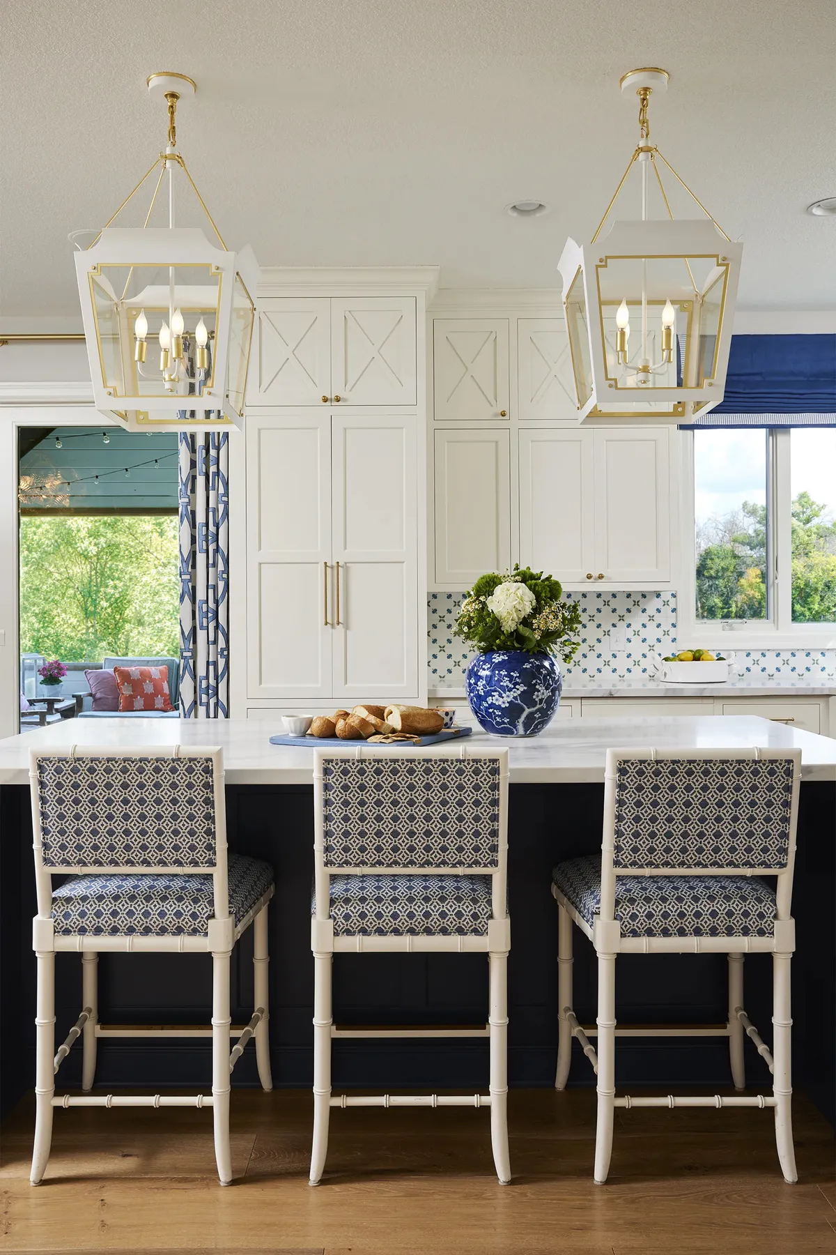 Bright white luxury kitchen with custom cabinetry, dual white open lantern pendant lights, and a matching kitchen island
